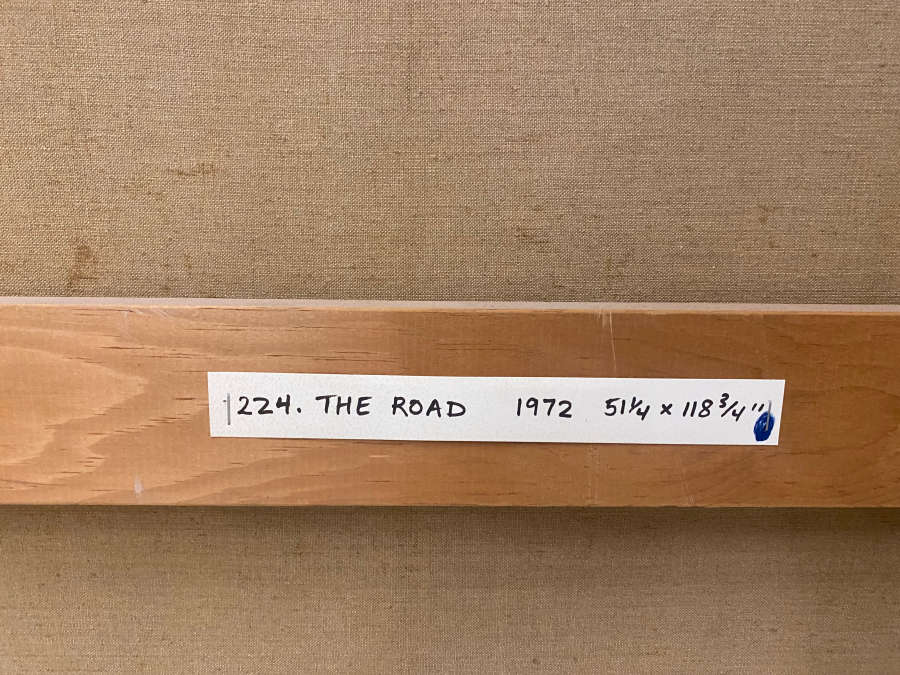 Back of a canvas with a white label on the wooden stretcher reading “224. The Road 1972 51¼ × 118¾” handwritten in black ink.