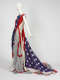 Side view of sleeveless dress designed from a red, white, and blue stars-and-stripes fabric, resembling the American flag, with sheer gray fabric cascading to the floor in a sweeping train.