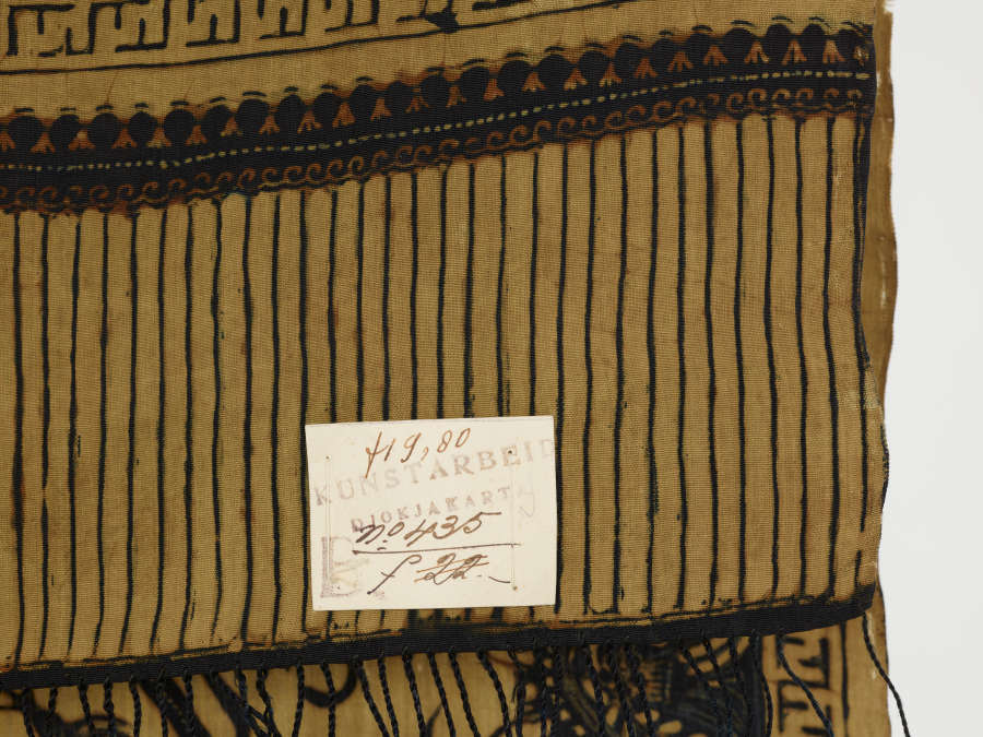 Detail of the bottom edge of the tan cloth, showing long vertical stripes formed by black threads. A faded small label reads “fig 80”.