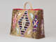 Fur-covered rectangular bag with thin looped handles, featuring central beaded seal silhouette within a black striped diamond, surrounded by red-blue patterned seals and multi-colored tassels, including a brown side panel. 