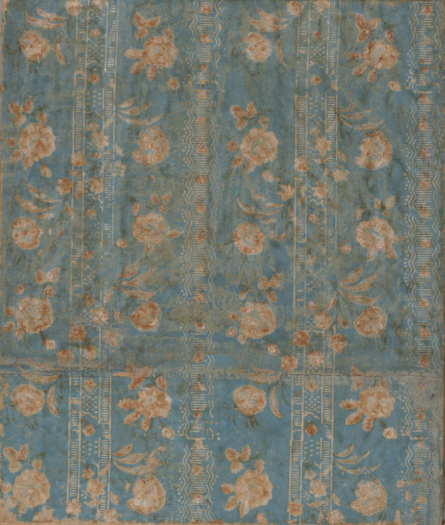 Segment of yellowed, vintage wallpaper featuring repeating columns of ornate copper florals and intricate borders against an aged teal background.