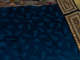 A close-up of deep blue fabric with a subtle woven pattern of animal figures, accented by a gold and black border. 