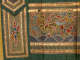 A mythological hoofed creature with red cloud-like wings surrounded by colorful clouds floating above blue waves, framed by horizontal gold bands, next to a long gold-detailed green folded layer.