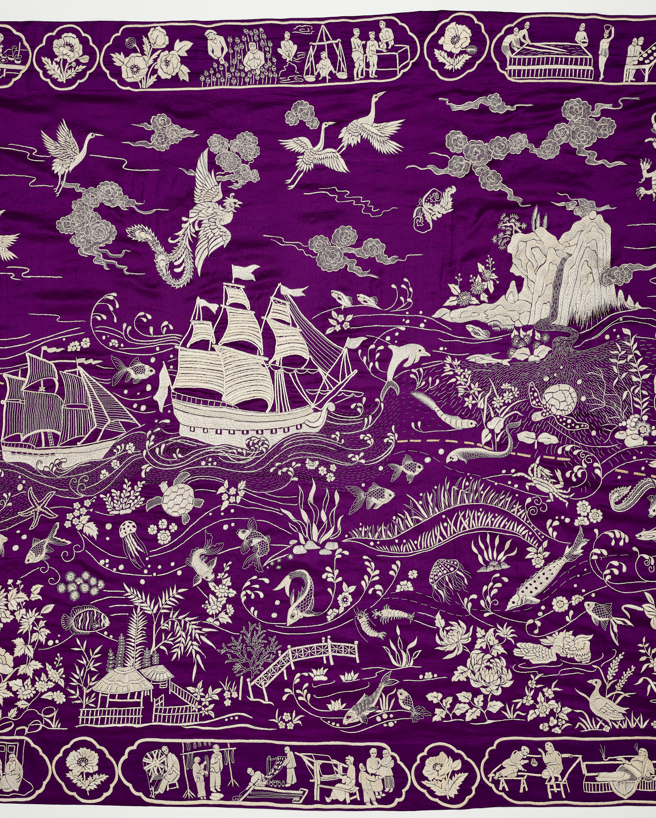 Detail from a purple and white embroidered textile depicting many scenes along a trade route, such as sailing ships, laborers and scenes of leisure.