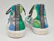 Back view of high top sneakers with blue and green abstract design and black zig zag strip down the back.