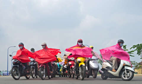 a group of people on scooters wearing pink and red ponchos