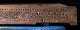 A carved wooden beam with repeating geometric motifs, with slight evidence of age and damage. 