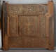 A carved wooden panel featuring intricately carved calligraphy along the top edge, a central geometric star pattern, and interwoven floral motifs, with signs of wear along the edges. 