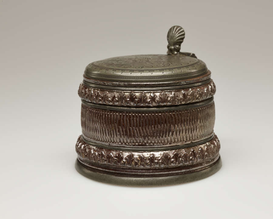 A brown and tan mug with a silver, scalloped rim.