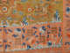 A golden dragon among red flames and blue clouds, bordered by orange panels with blue floral motifs, stylized waves, and geometric patterns.
