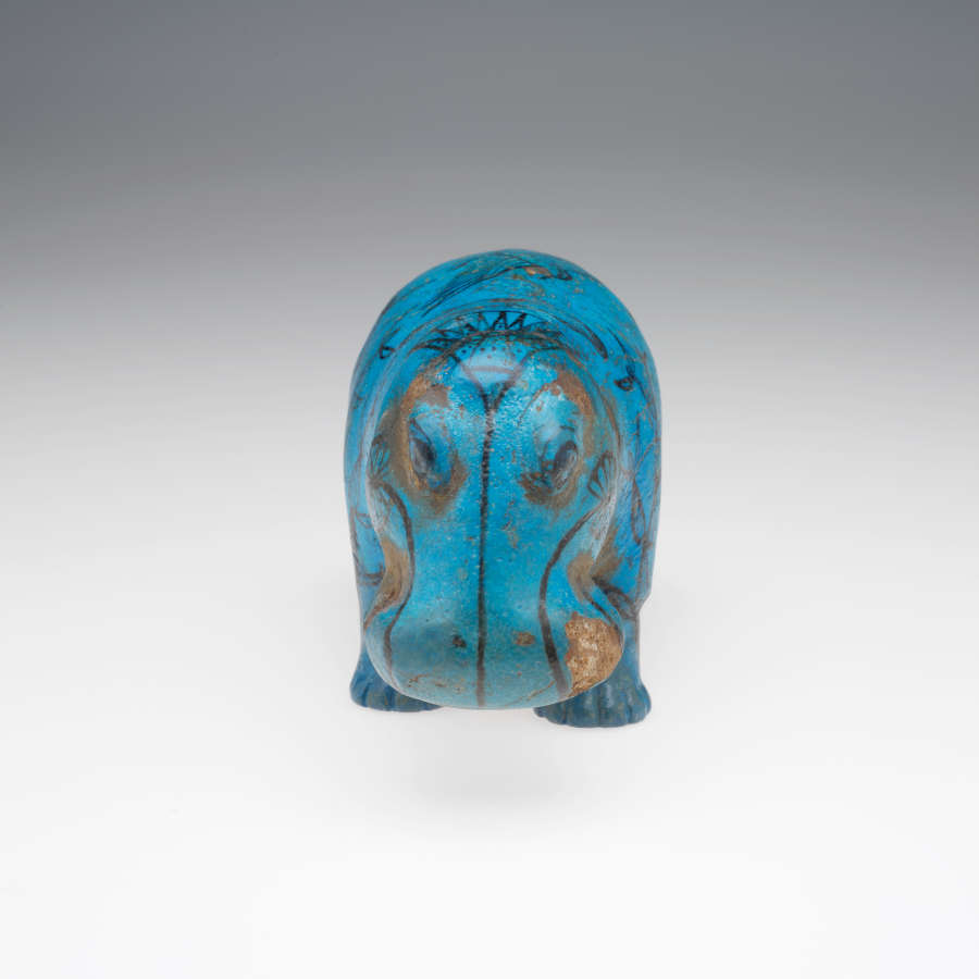 Front view of a blue hippopotamus sculpture – its bowed head in focus, with black linework and brown, chipped swirls of the face blending into floral motifs.