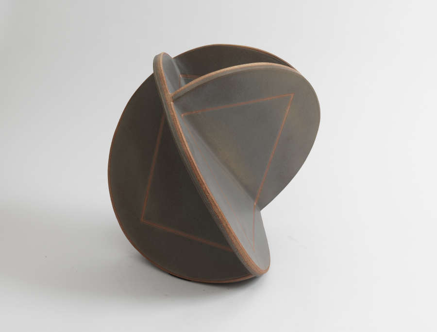 Intersecting matte black ceramic discs forming a partial sphere shape, each disc segment marked with a faint triangular design on the surface and thin reddish-brown rims.