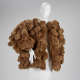 Bulky sculptural waist-length brown coat constructed entirely of densely packed, soft, plush teddy bear stuffed animal forms draped over a white mannequin.