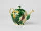 A bulbous teapot with white, green, and yellow floral decorations in the form of a leafy pineapple.