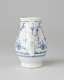A white chocolate pot with delicate blue decorations with ribbed body, spout, handle, and foot.