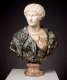Realistic marble bust depicting a stoic woman whose clothes contrast with the smooth white marble of the bust, the outermost layer being textured black and gray stone, and the innermost tan and striped.