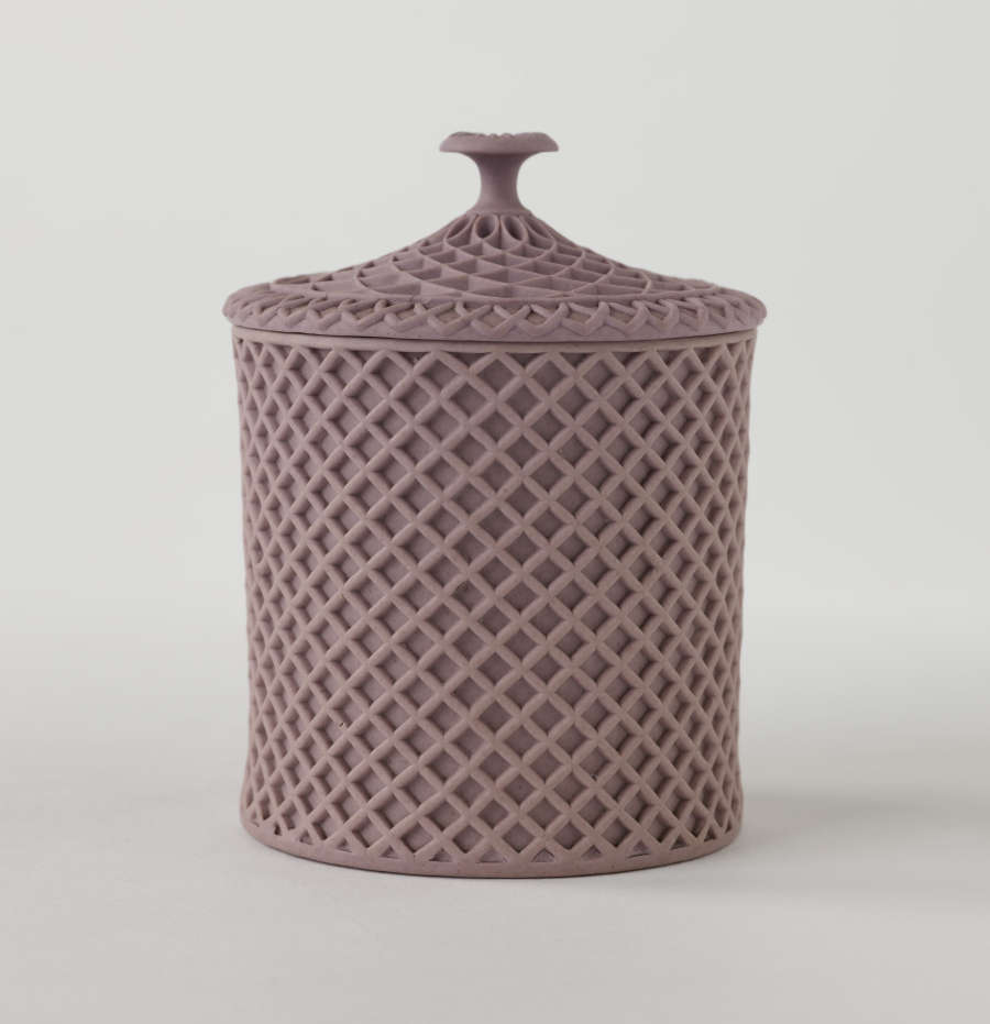 A purple covered cup with raised woven texture. The handle is sculptural and swirled.