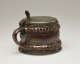 A brown and tan mug with a silver, scalloped rim.