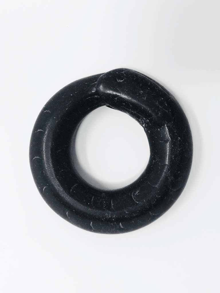 White-speckled black stone amulet of a thick-bodied snake biting its own tail, forming a circle. Etchings detail the snake's scales and eyes.