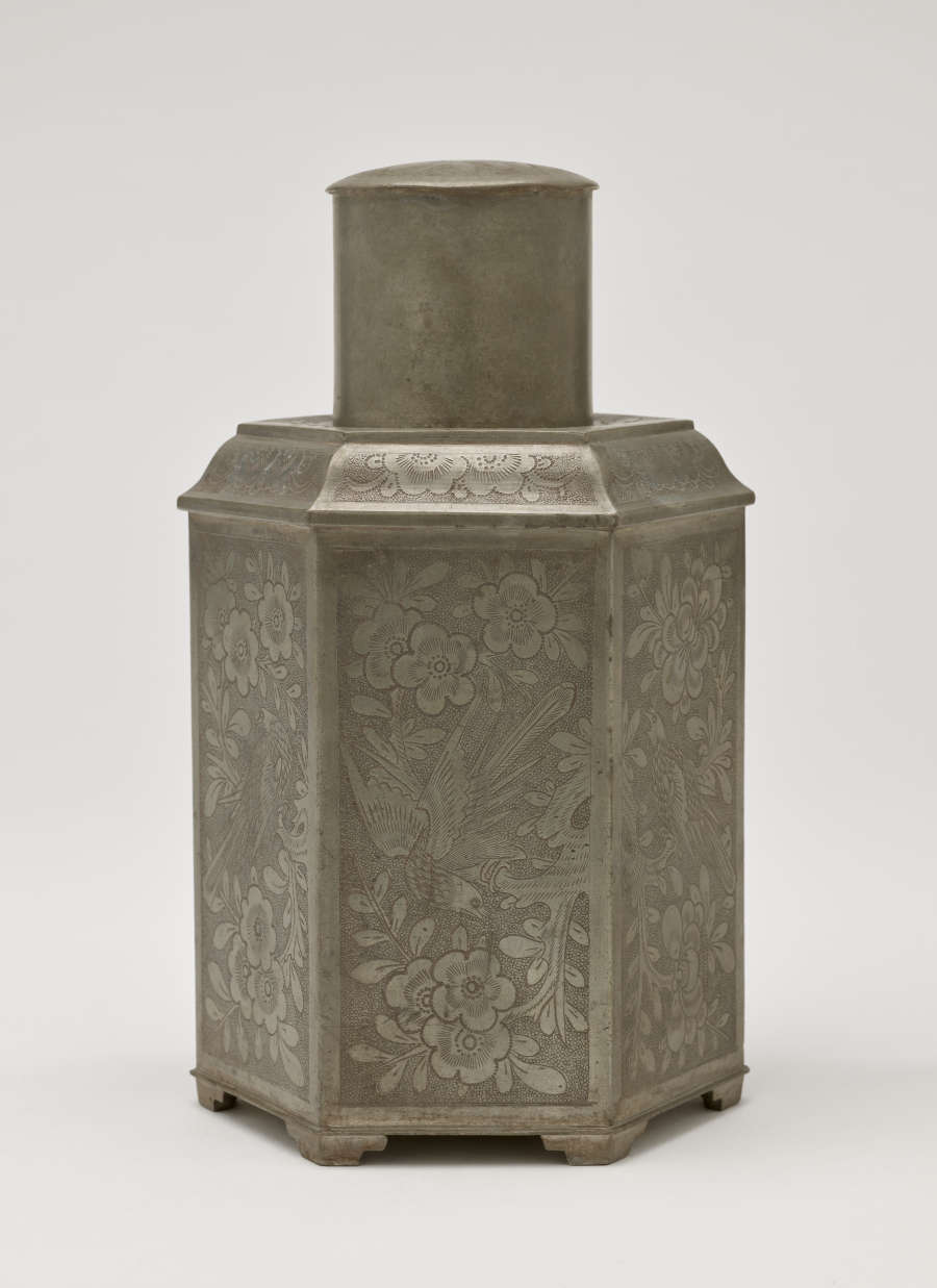 A pentagonal pewter tea caddy with floral decorations.