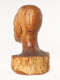 Three quarter back view of a glossy wooden bust depicting the back of the head of a  male figure. The wood features long vertical cracks, carving marks and color variation.