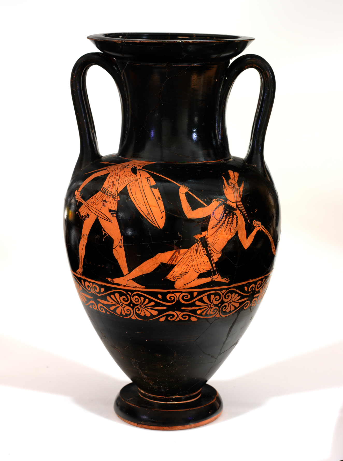 Black vessel with two symmetrical handles. The surface is decorated by an orange illustration of two warriors in combat, one holding a sword and shield and the other a spear.