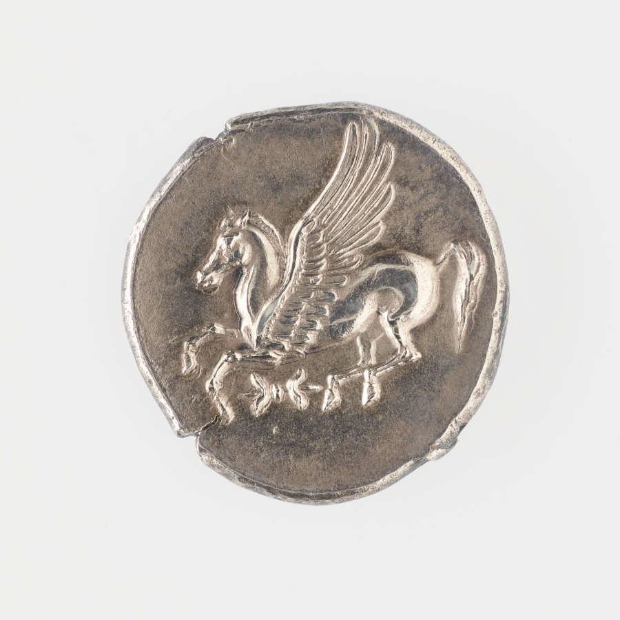 Round silver coin with irregular edges, embossed with a winged horse and a bow-like motif underneath.