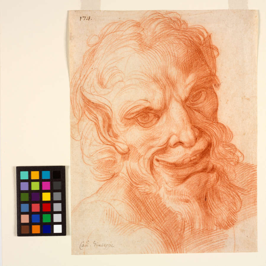 Red chalk drawing of a smiling satyr’s head with delicate marks throughout and vigorous crosshatching at the chest. He has pointed ears and curly hair and beard.