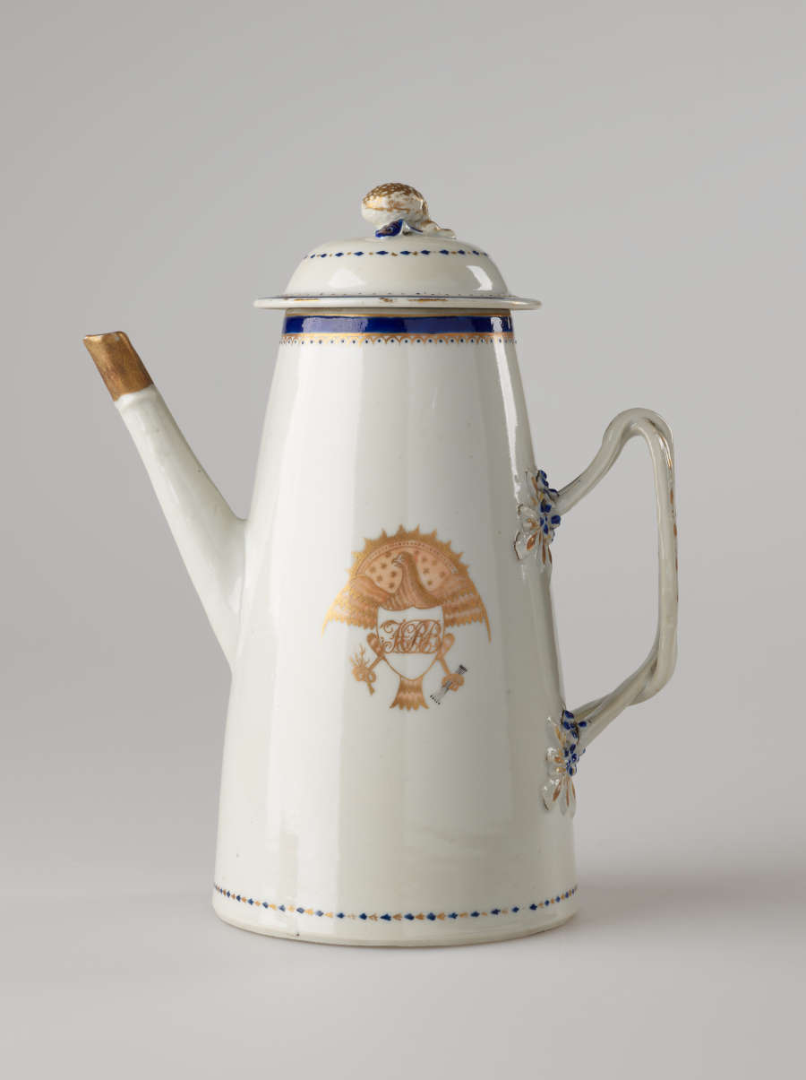 A white, blue and gilded teapot with a long straight spout, a handle, and lid. The central decoration depicts a heraldry bird with a shield and objects in its talons.