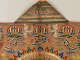 The back of a green and gold embroidered robe collar with symmetrical white birds beneath and gold, red, green, and blue emblems and clouds on an orange silk background. 