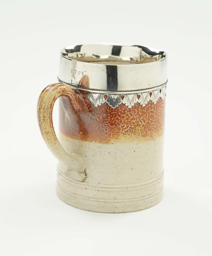 A brown and tan mug with a silver, scalloped rim.