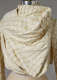 Close up of a cream colored, draped garment with a raised, netting pattern and soft folds draping across the chest. 