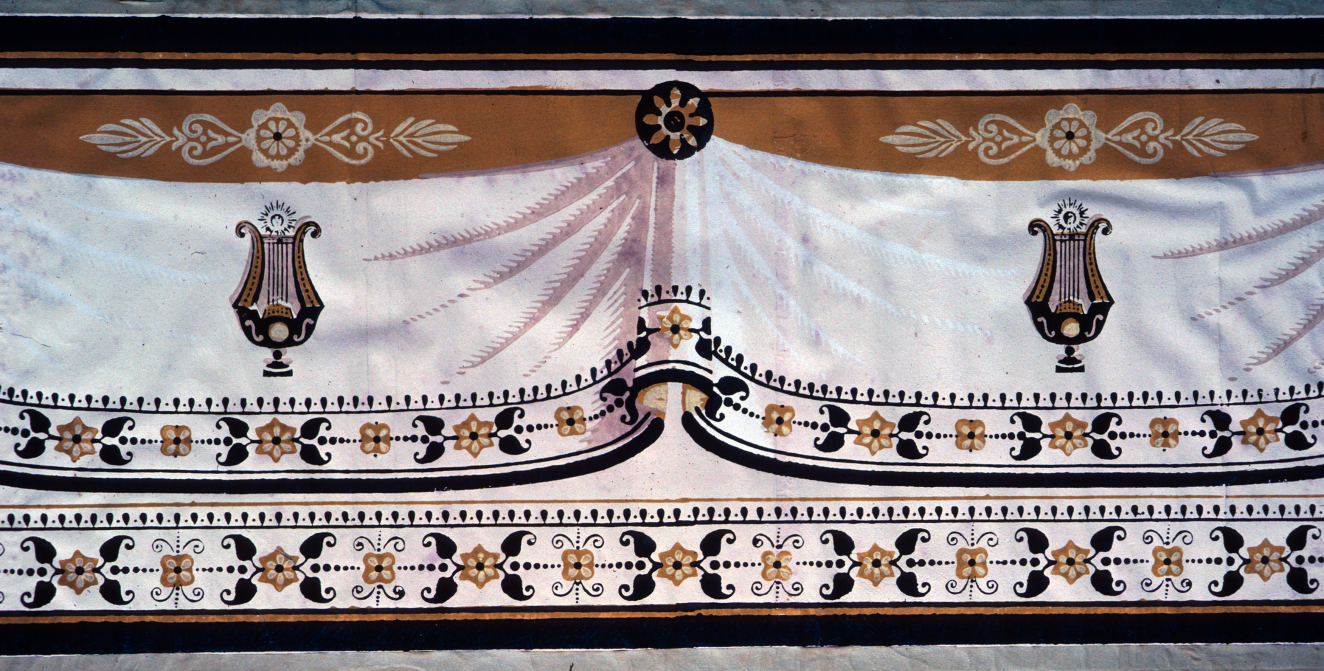 Decorative frieze featuring a swagged curtain illusion, lyres, and a trim of stylized flowers and leaves. The palette consists of white, black, and brown with pops of yellow.