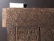 A close up of an intricately carved wooden corner with interlocking diamonds and ornate floral motifs. 
