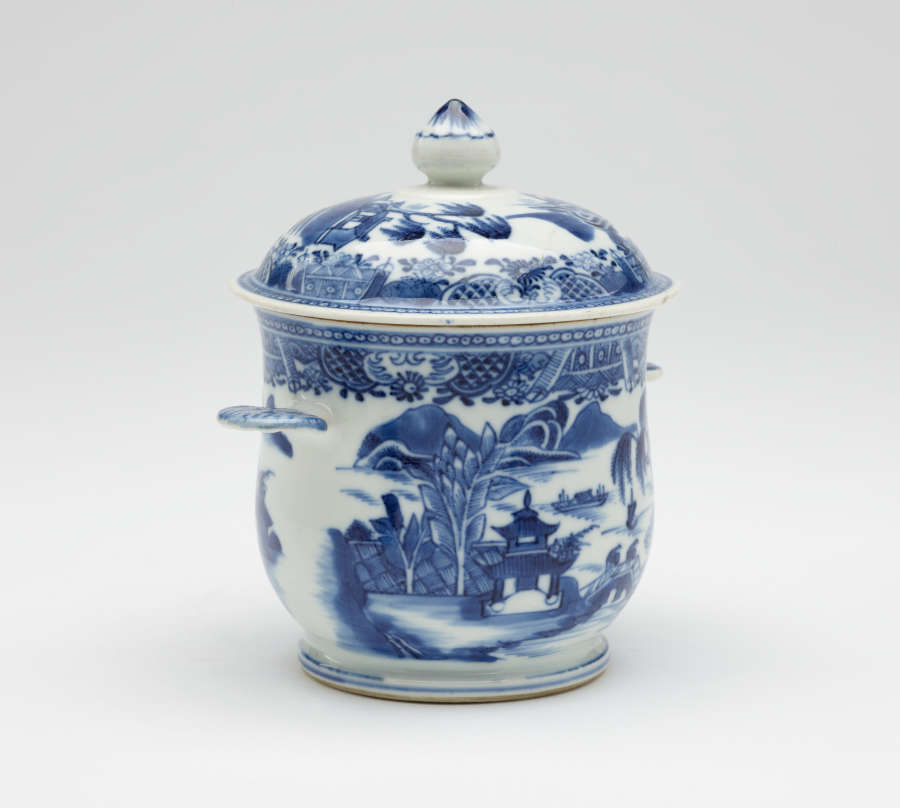 A white bowl with flat handles and lid. The blue decorations are architectural and floral.