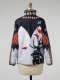 Back of a windbreaker on a mannequin. Its top features a black angular design with red-orange feather and shell-motifs. Its white bottom features the silhouette of an antlered animal.