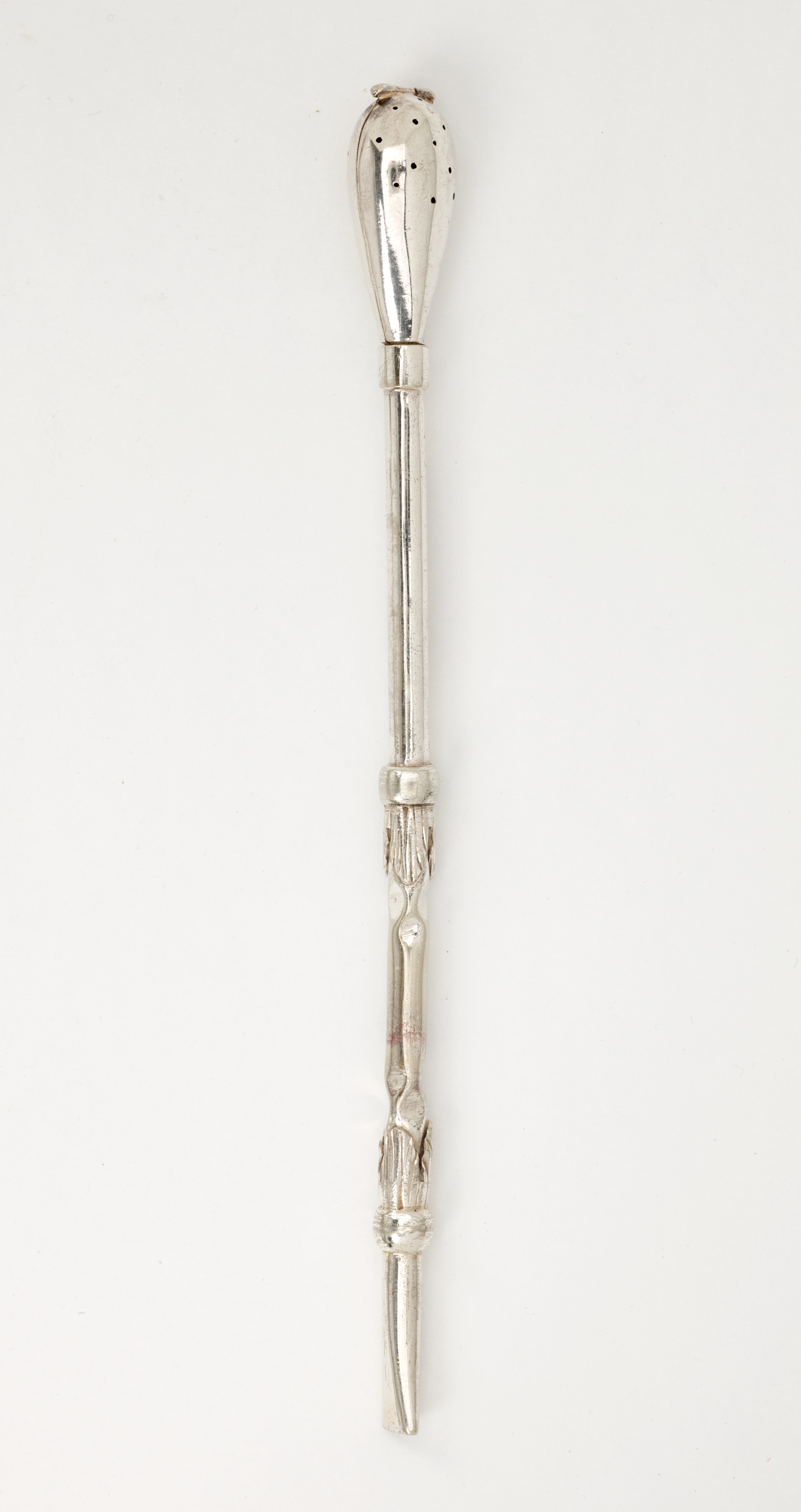 A silver utensil with a long skinny handle and bulbous end with small holes.