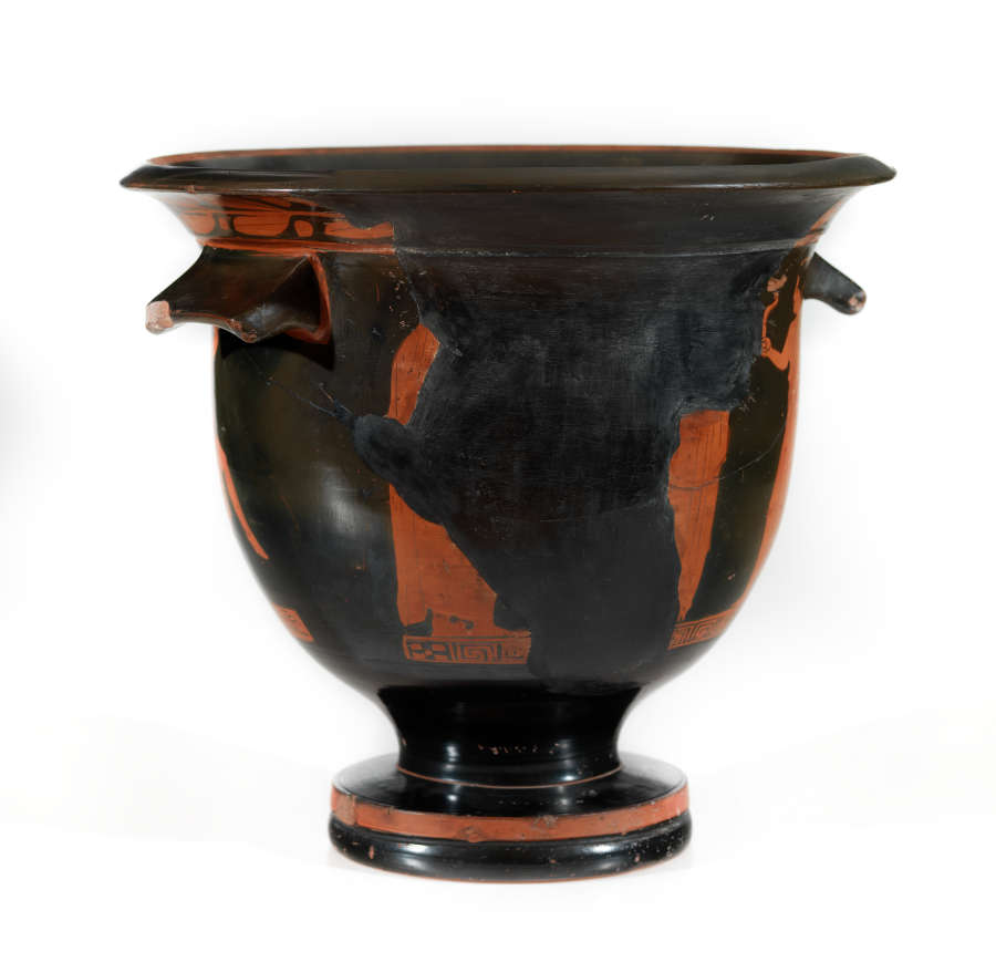Another view of a stout black bowl with a wide foot, two handles and a flared mouth. The terracotta illustrations and patterns decorating it are fragmented, separated by black filling.