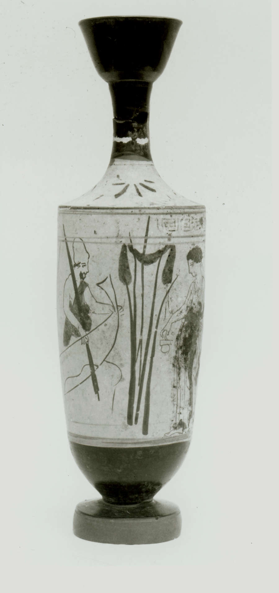 Monochromatic image of a vase with a narrow fluted neck and thick foot. It’s decorated with illustrations of a figure in a boat facing another standing figure, divided by reeds.