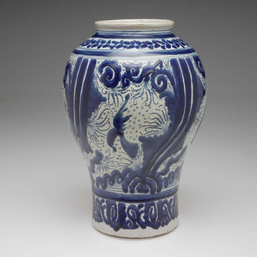 A vessel with a cylindrical bottom and bulbous top. Covered in white and blue abstract decoration