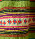Another detail of the pattern. A thick strip of off-white with red and blue squares woven through it is surrounded by wavy horizontal orange, black, purple, pink, and yellow stripes. 