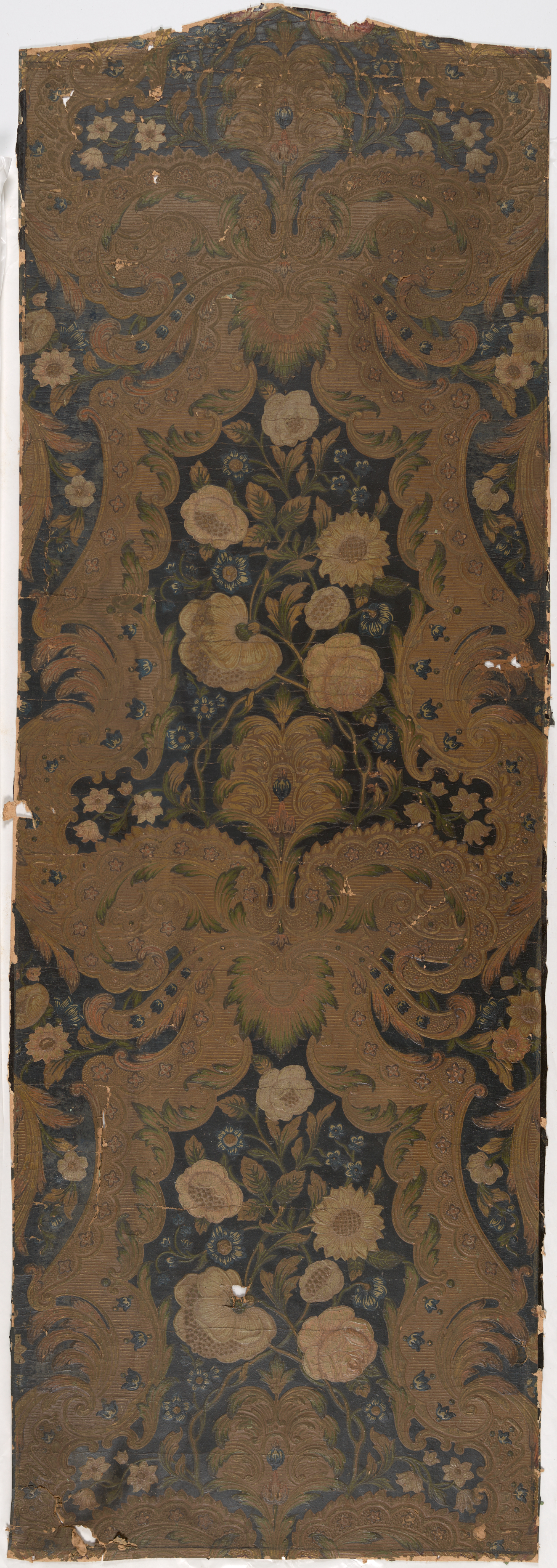 Tall, narrow panel of aged wallpaper featuring a mirrored pattern of intricate, golden botanical motifs against a dark, worn background.