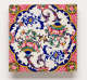 Square wall tile. It features floral pink and green motifs connecting into swirling blue motifs to form a circle. The corners are pink and red patterned with yellow floral motifs.