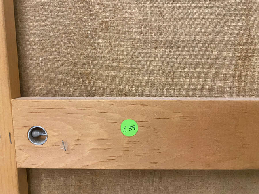 Back of canvas showing horizontal wooden support featuring a green sticker marked “C39” and a visible metal screw fixture.
