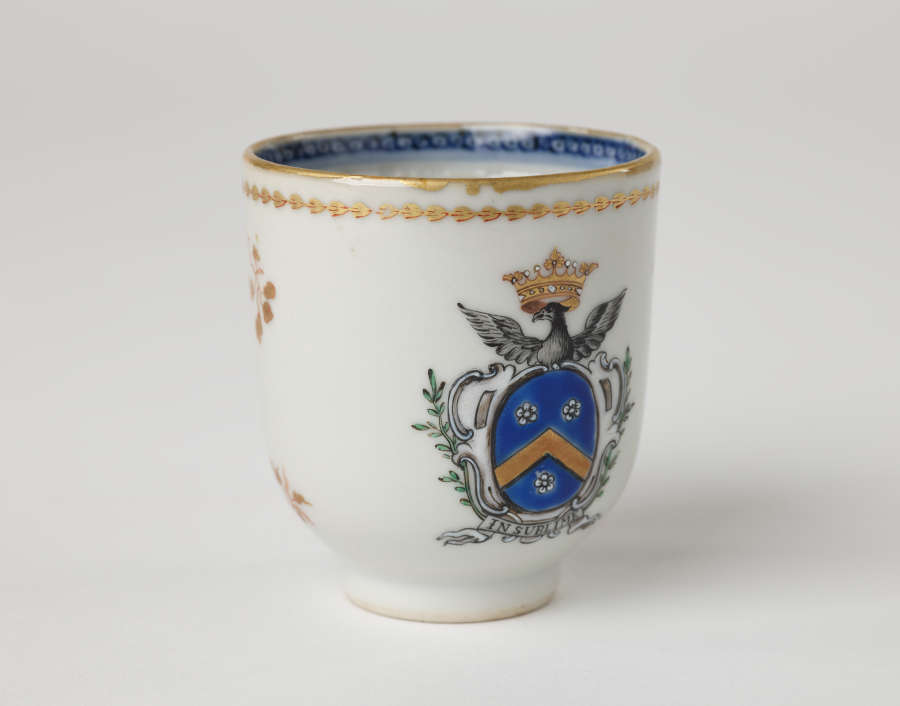 A cup with blue and gilded decorations along the outside and inside of the rim, body, and handle.