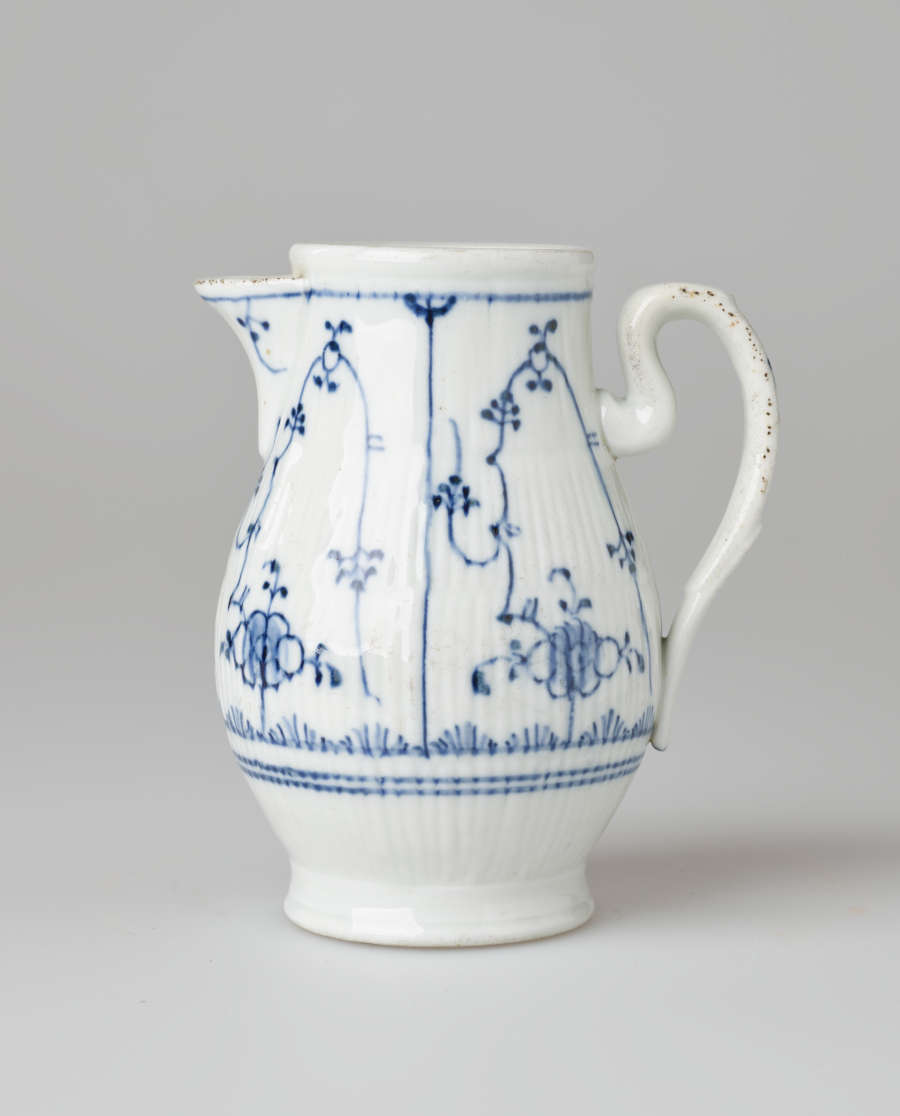 A white chocolate pot with delicate blue decorations with ribbed body, spout, handle, and foot.