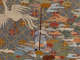 Robe’s back detail. A standing monk holds a tall staff amongst earthy pastel clouds and a soaring bird, against a blue-gray background with a diagonally running grid and floral motifs.