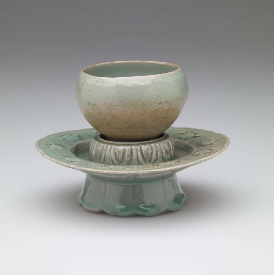 A rounded vessel sitting on a pedestal with a scalloped foot.