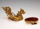 Detached top and bottom of a golden dragon-like bird container with embedded gems. The lid forms dragon-like bird’s body, while the base is a cup-like stand with a red interior.