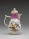 A white coffee pot with gold, pink, and floral decorations. The central decoration has two birds perched on branches.